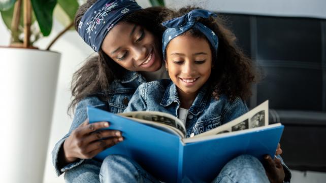 A person and a child reading a book Description automatically generated
