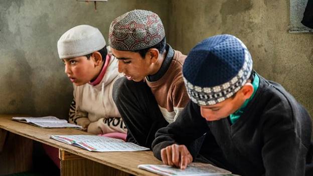 A group of boys sitting at a desk Description automatically generated