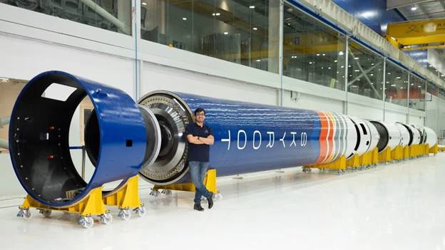 A person standing next to a large blue and white cylindrical object Description automatically generated
