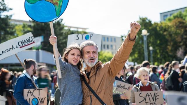 A person and a child holding signs Description automatically generated