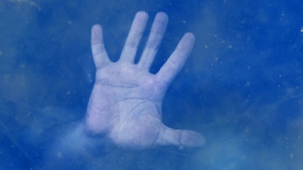 frozen man with hand against a blue snowy background.