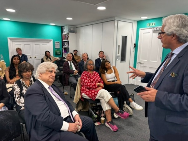 A person in a suit speaking to a group of people  AI-generated content may be incorrect.