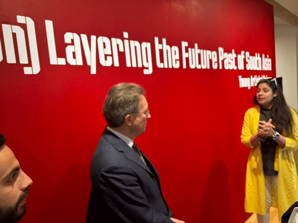 A person and person standing in front of a red wall  AI-generated content may be incorrect.