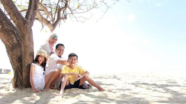 A family sitting on sand under a tree  AI-generated content may be incorrect.