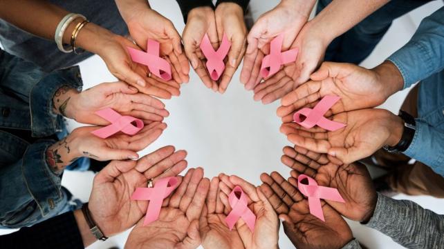 A group of hands holding pink ribbons  AI-generated content may be incorrect.