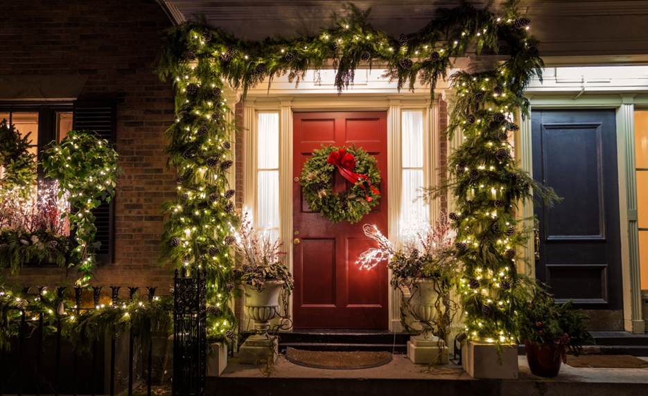 A red door with a wreath and lights on it Description automatically generated