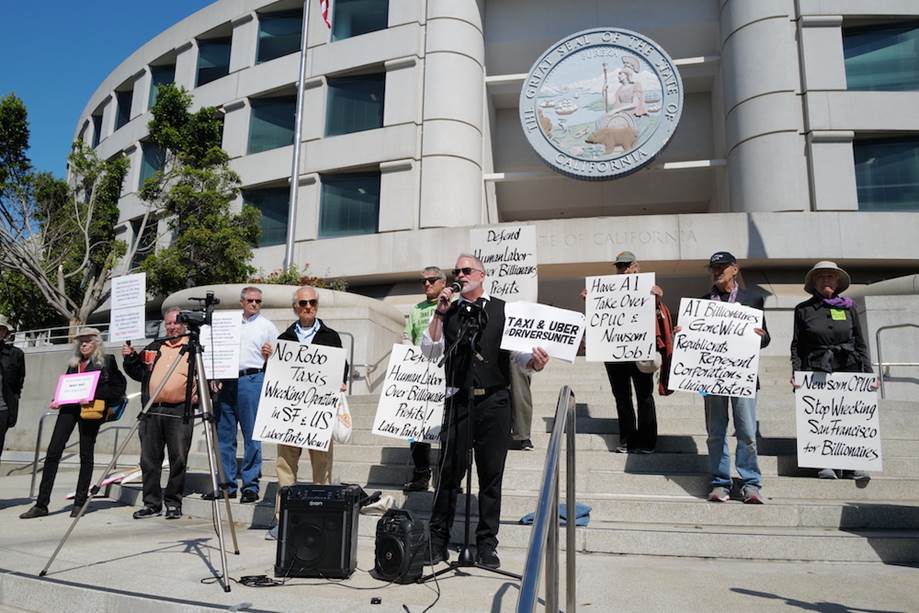 A group of people holding signs outside of a building Description automatically generated