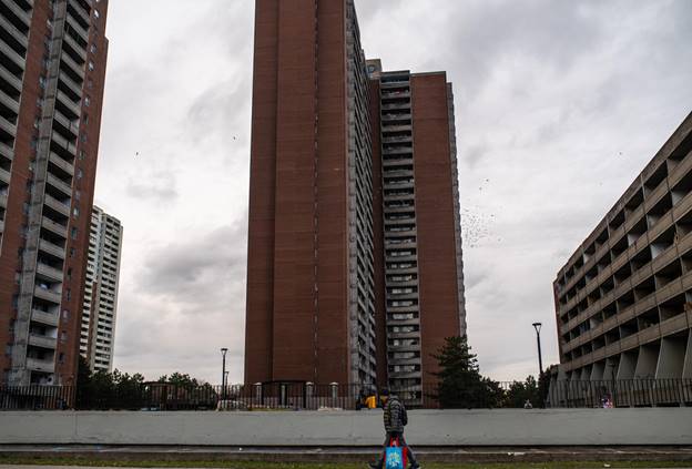 A man carries his bags near high-rises on a cloudy day