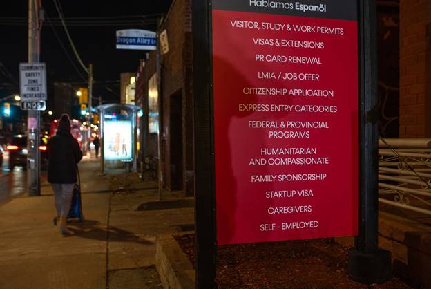 A red sign with white lettering on an urban street at night.