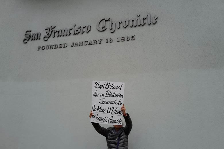A person holding a sign in front of a building Description automatically generated