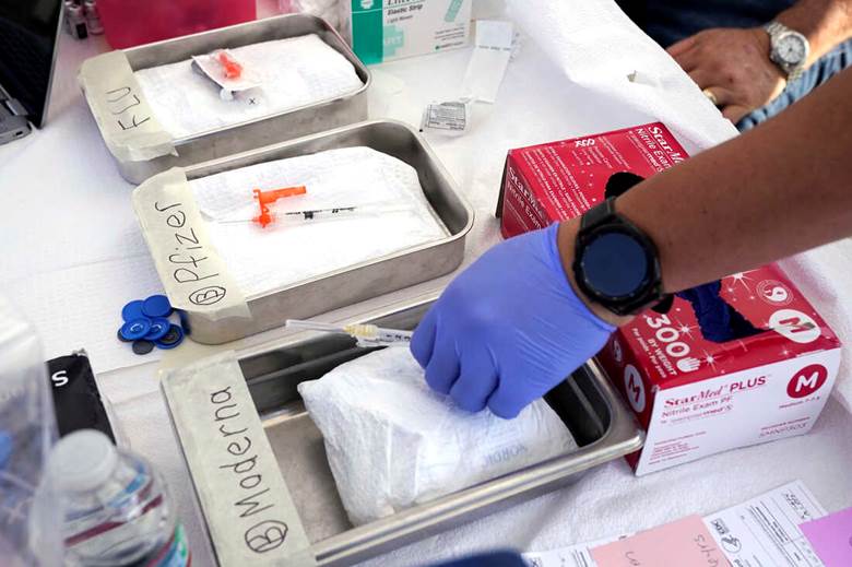 A person in gloves putting a syringe into a tray Description automatically generated