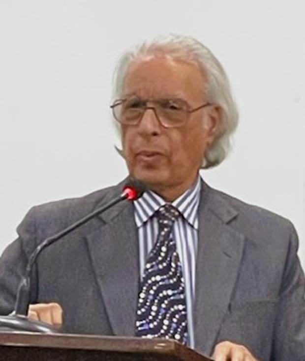 A person in a suit speaking into a microphone Description automatically generated