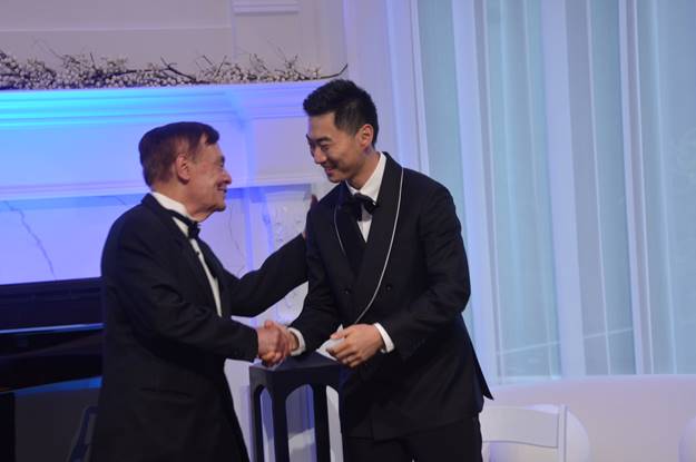 Two men in suits shaking hands Description automatically generated
