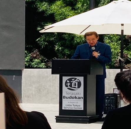 A person standing at a podium with a microphone Description automatically generated