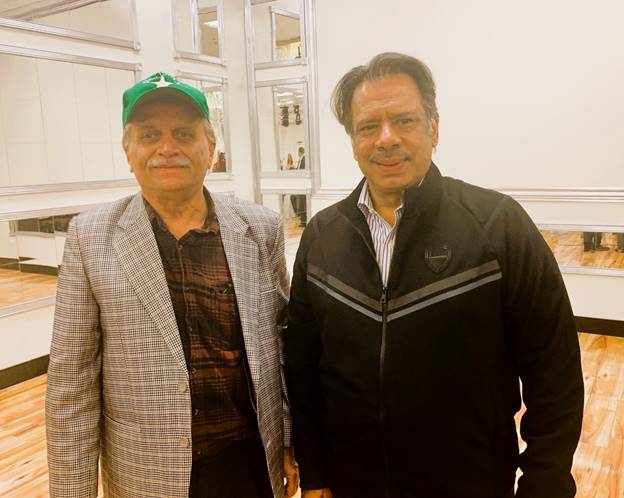 Two men standing together smiling Description automatically generated