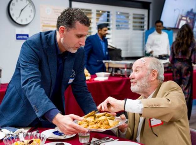 Dr. Ahmed Soboh, left, religious director at the Islamic Center of Yorba Linda offers Rabbi Joseph Mendelsohn snacks minutes after the breaking of the fast at 7:04 p.m. during the ICYL’s annual Interfaith Iftar and Dinner in Yorba Linda on Wednesday, March 20, 2024. (Photo by Leonard Ortiz, Orange County Register/SCNG)