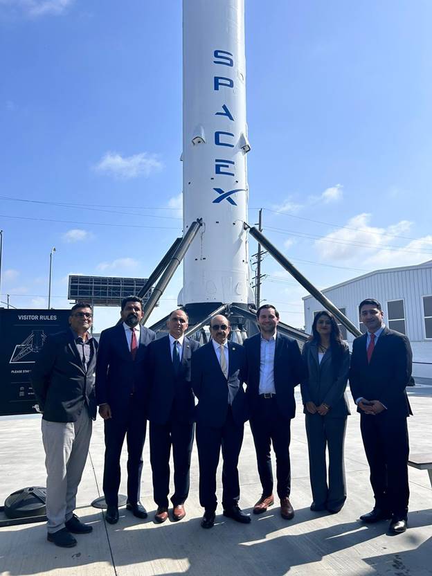 A group of people standing in front of a rocket Description automatically generated