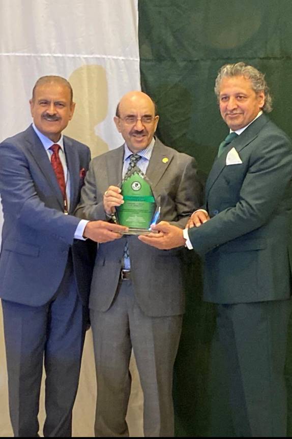 A group of men in suits holding a green award Description automatically generated
