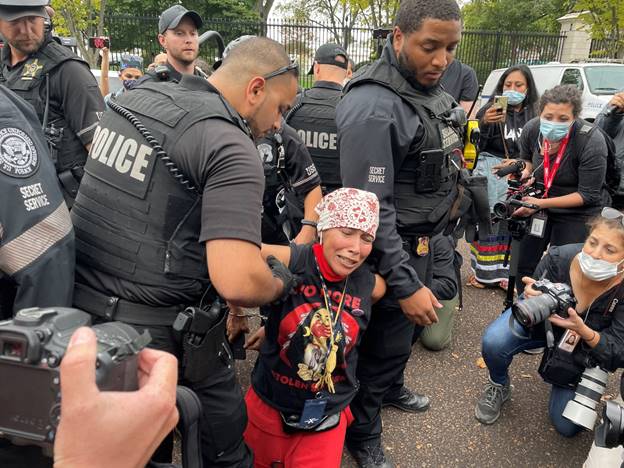 A group of police officers holding a person Description automatically generated