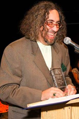 A person with curly hair and a microphone Description automatically generated