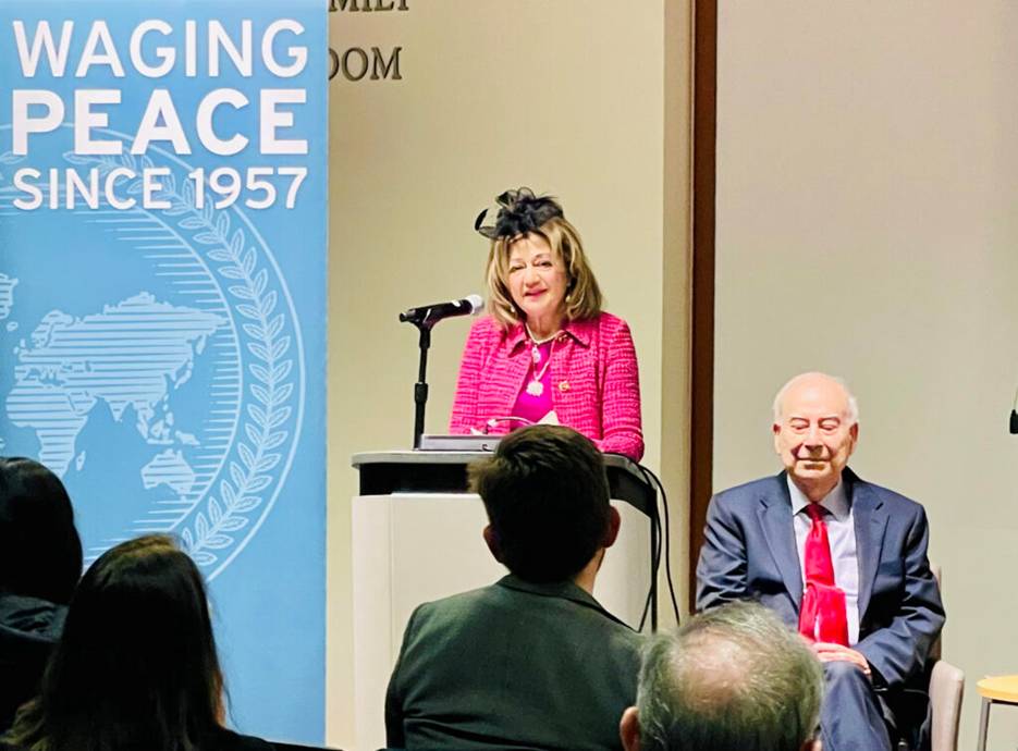 A person standing at a podium with a microphone and a person sitting in front of him  AI-generated content may be incorrect.