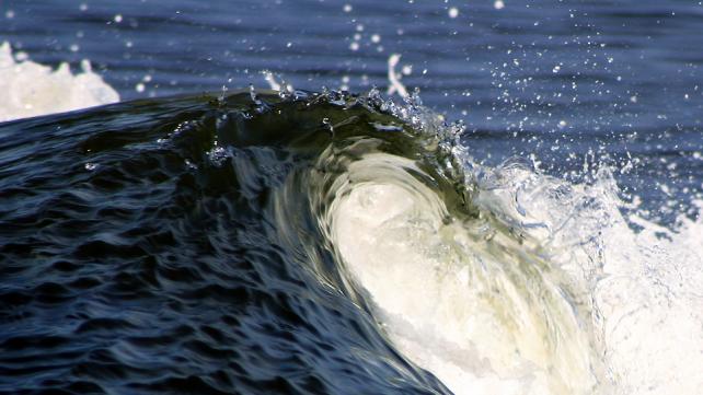 A wave in the ocean Description automatically generated with low confidence