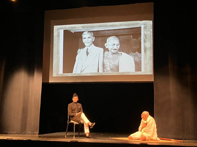 A person sitting on a stage with a person on his lap Description automatically generated