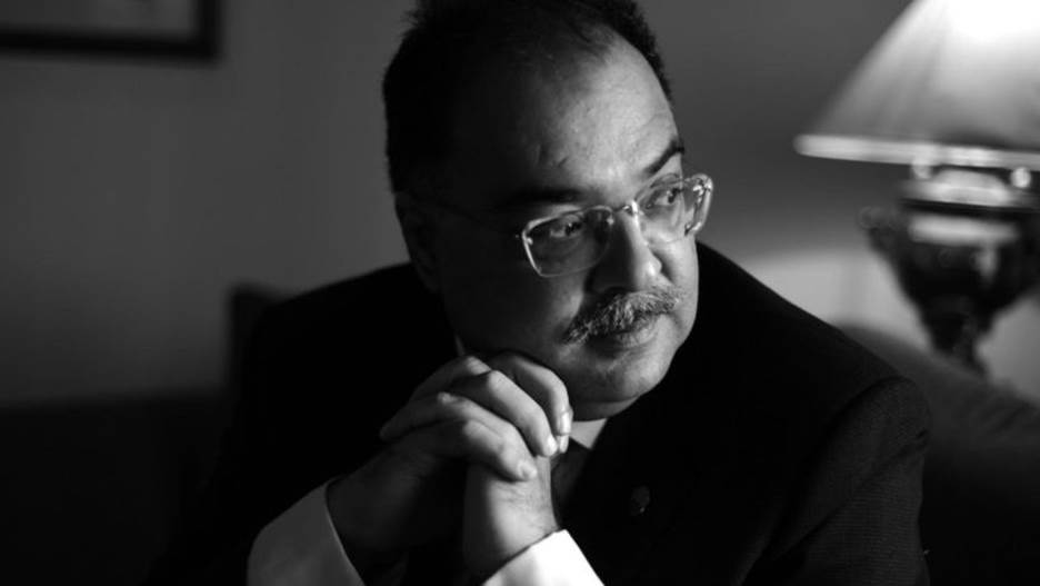 A person in a suit and glasses Description automatically generated