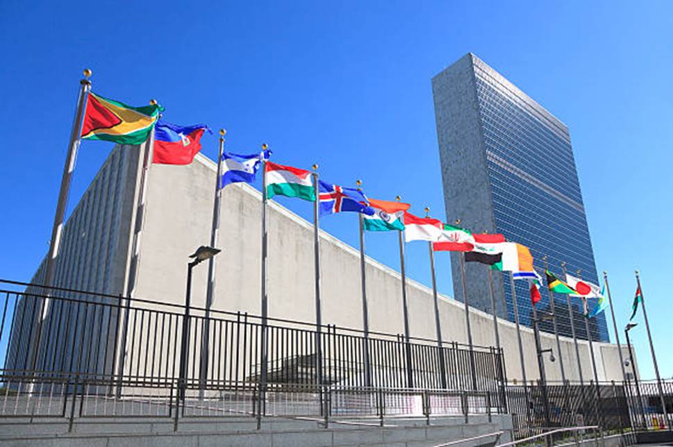 A group of flags in front of Headquarters of the United Nations Description automatically generated