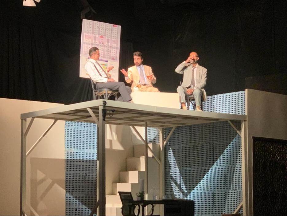 A group of men sitting on a stage  Description automatically generated