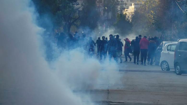 A group of people walking on a street with smoke Description automatically generated