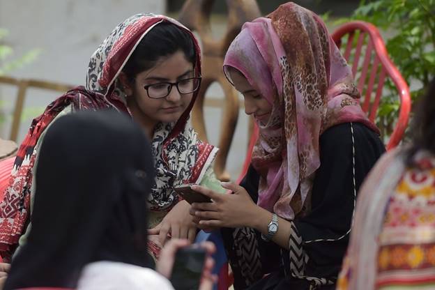 A group of women wearing headscarves looking at a book Description automatically generated