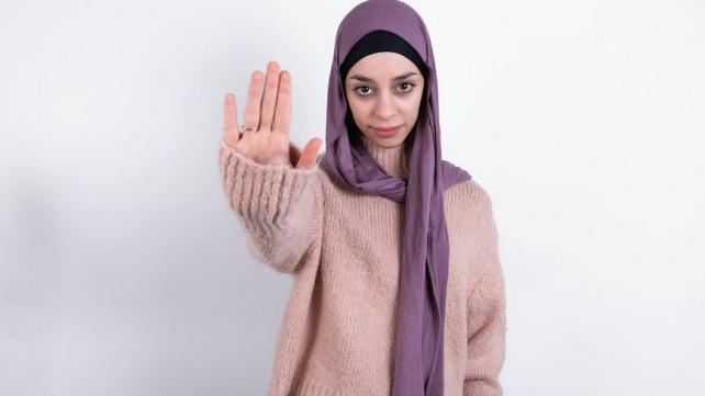 A person wearing a scarf and holding up her hand Description automatically generated