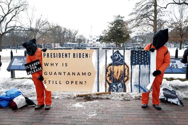 A group of men holding a sign Description automatically generated