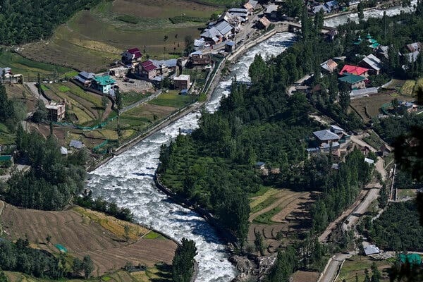 A view from the air of a river running through an area with trees, houses and fields.