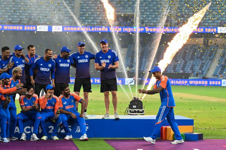 TOPSHOT - India's captain Suryakumar Yadav (R) playfully pretends to hold the trophy as his team celebrates their victory at the end of the Asia Cup 2025 Twenty20 international cricket final match between India and Pakistan at the Dubai International Stadium in Dubai on September 28, 2025.