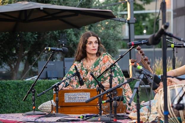 A person sitting at a stage with microphones  AI-generated content may be incorrect.